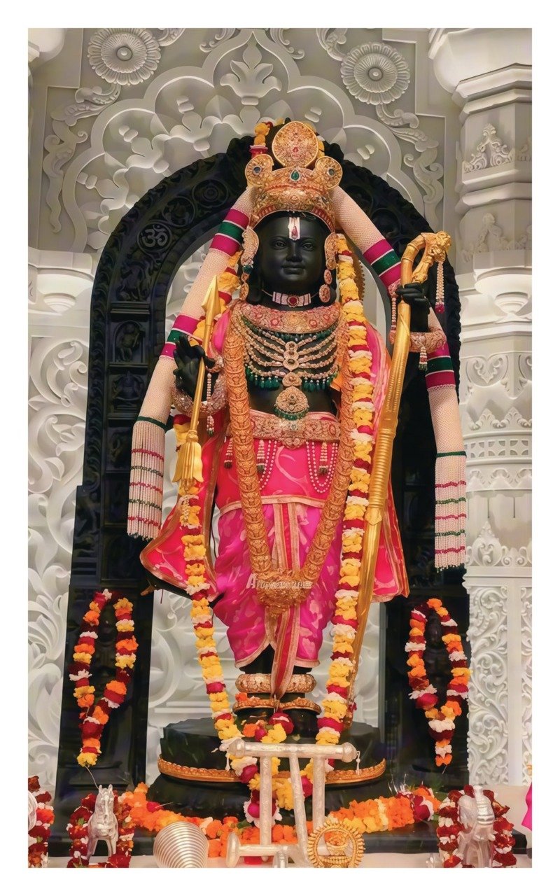 Black stone idol of child Rama in pink silk and gold crown with bow, garlanded in a white marble sanctum